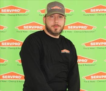 male employee sitting in front of SERVPRO backdrop