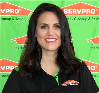 female worker sitting in front of a SERVPRO backdrop