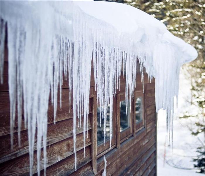image of large ice dam hanging over roof of a home